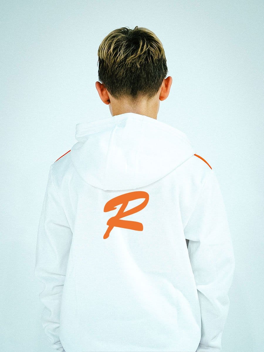 Rückansicht eines jungen Mannes mit kurzen, zweifarbigen Haaren, trägt eine weiße Jacke mit einem großen orangefarbenen "R" auf dem Rücken.