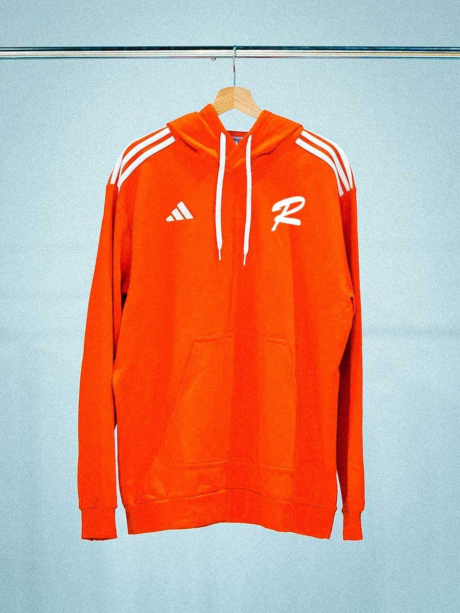 Oranger Hoodie mit weißen Streifen auf den Schultern, Logo auf Brust, Kängurutasche vorne, an Kleiderbügel hängend, vor hellem Hintergrund.