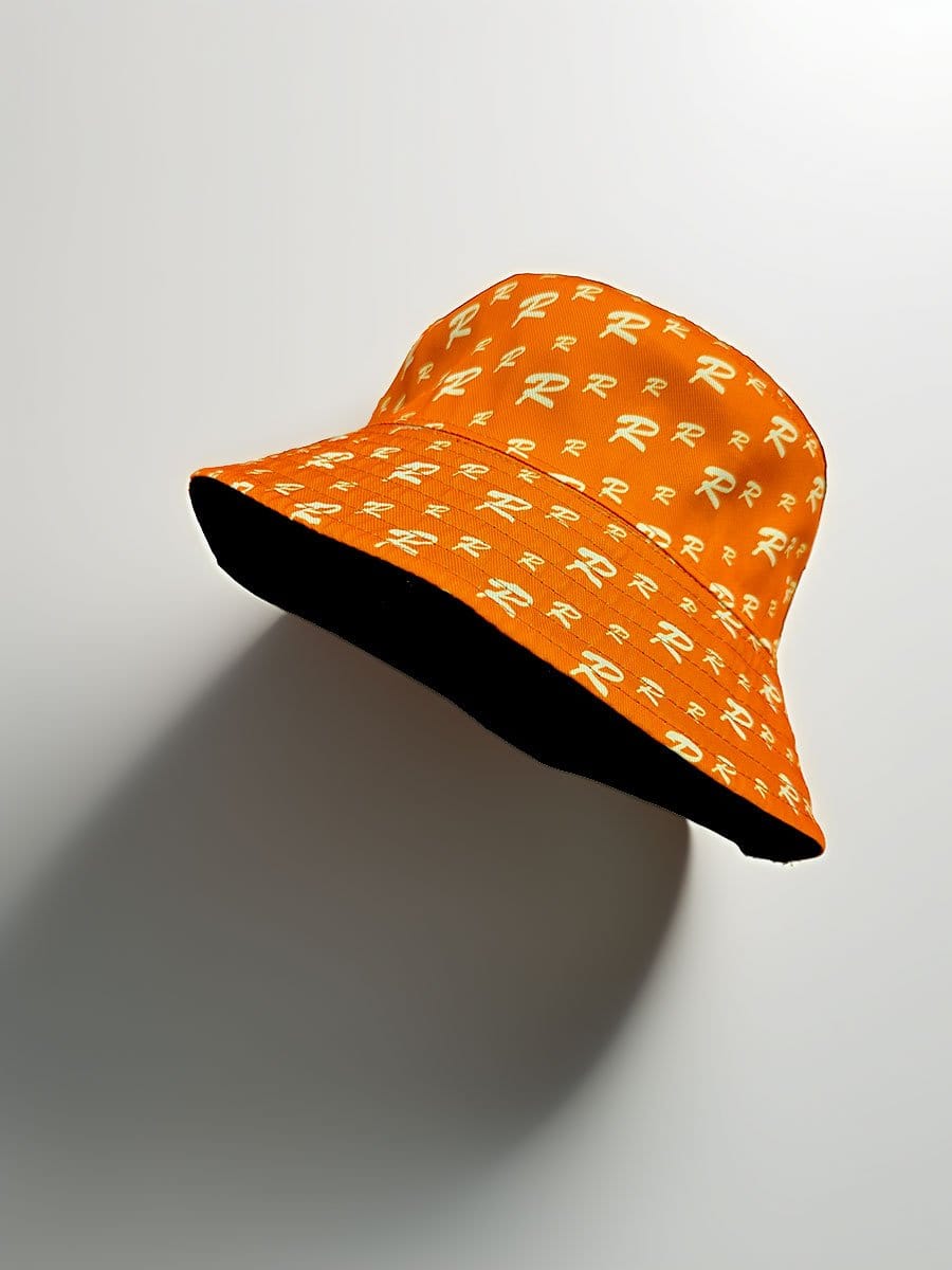 Orange Sonnenhut mit weißem R-Logo-Muster, breiter Krempe und schwarzem Innenfutter, liegt auf weißem Hintergrund.