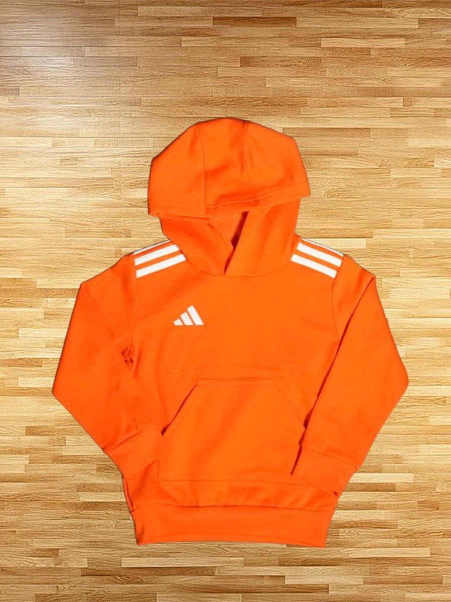 Ein orangefarbener Kapuzenpullover mit weißen Streifen auf den Schultern und einem Logo auf der Brust, liegt flach auf einem Holzboden.