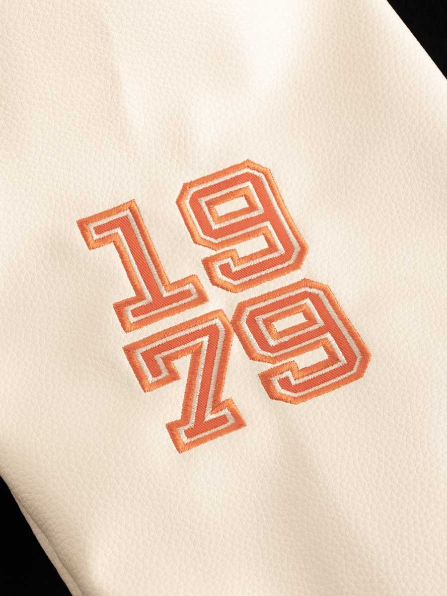 Weiße Oberfläche mit orangegestickter Zahl 1973 in sportlichem Blockstil.