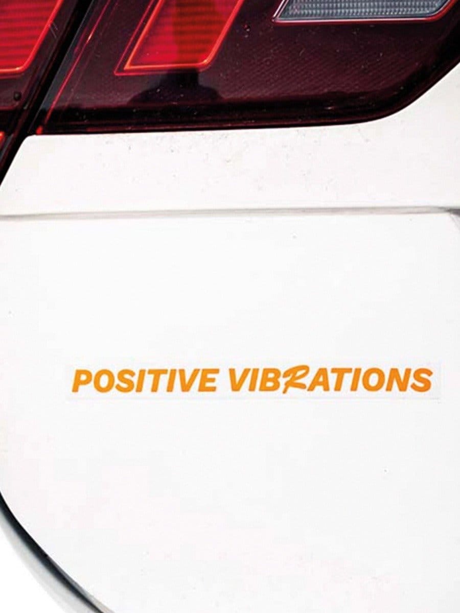 Nahaufnahme eines weißen Autos mit rotem Rücklicht und dem orangefarbenen Schriftzug "POSITIVE VIBRATIONS" auf der Karosserie.