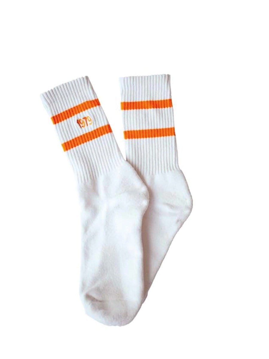 Weiße Socken mit orangefarbenen Streifen an den Bündchen, eine Socke zeigt das Logo "GTS" in Orange.