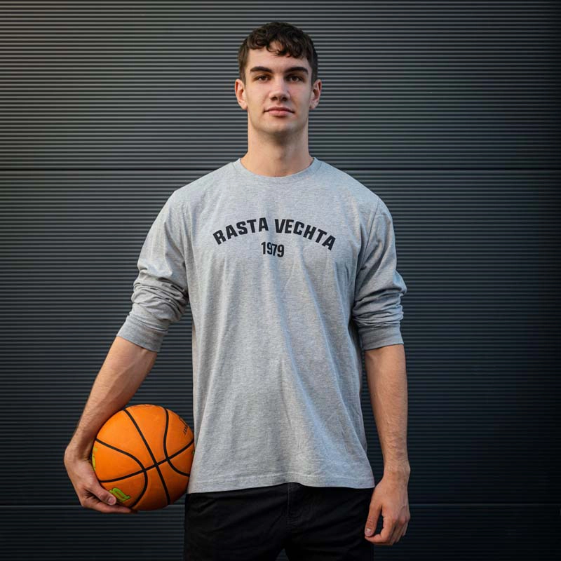 Mann mit Basketball in der Hand im Longsleeve 1979 in grau mit Rasta Vechta 1979 Aufdruck auf der Brust in schwarz.