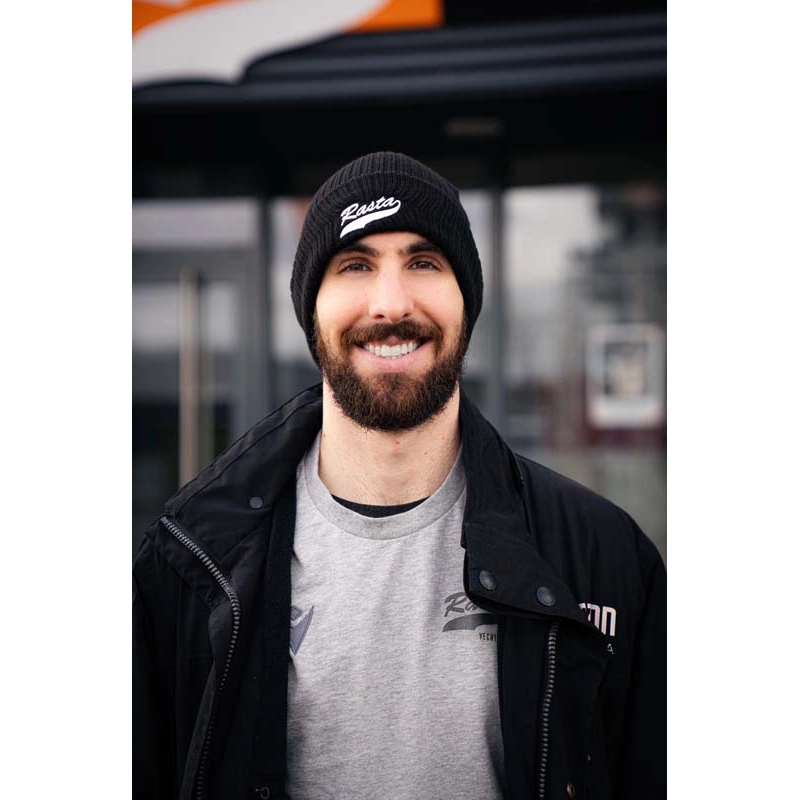 Mann mit Riffle Beanie in schwarz mit Rasta Schriftzug an der Krempe in weiß.