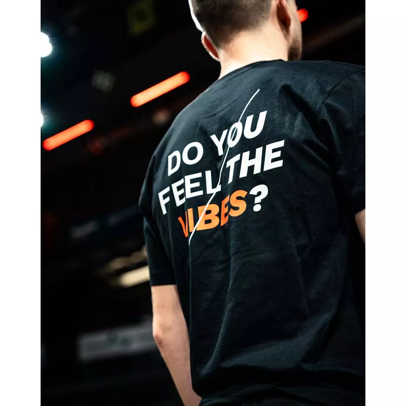 Mann von hinten im schwarzem T-Shirt mit Do yoe feel the Vibes? Aufdruck  in weiß Vibes in orange.