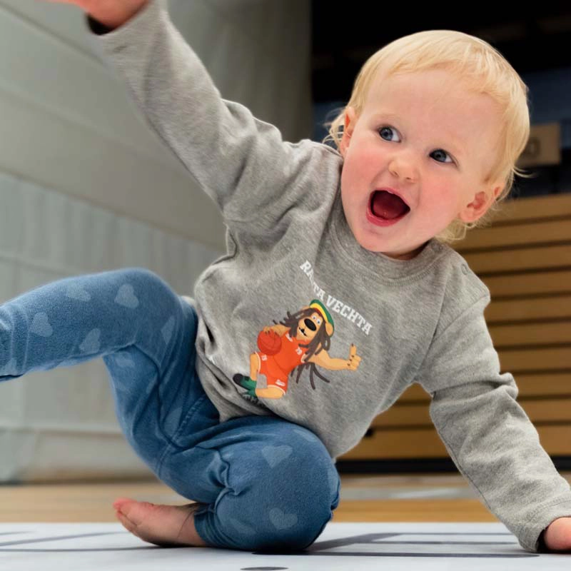 Kleinkind mit Baby Langarmshirt "Bob" in grau mit Maskottchen Bob Auf der Brust darüber Rasta Vechta darunter Basketball Schriftzug als Aufdruck in weiß. 