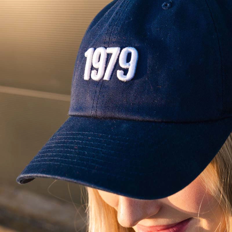 Frau mit Cap "1979" in marineblau von vorne mit Zahl 1979 aufgestickt in weiß.