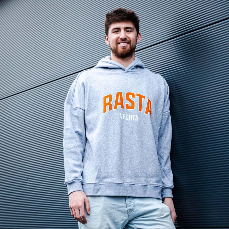 Mann von vorne im Hoodie grau mit Rasta Logo auf der Brust in  orange darunter Vechta in weiß.